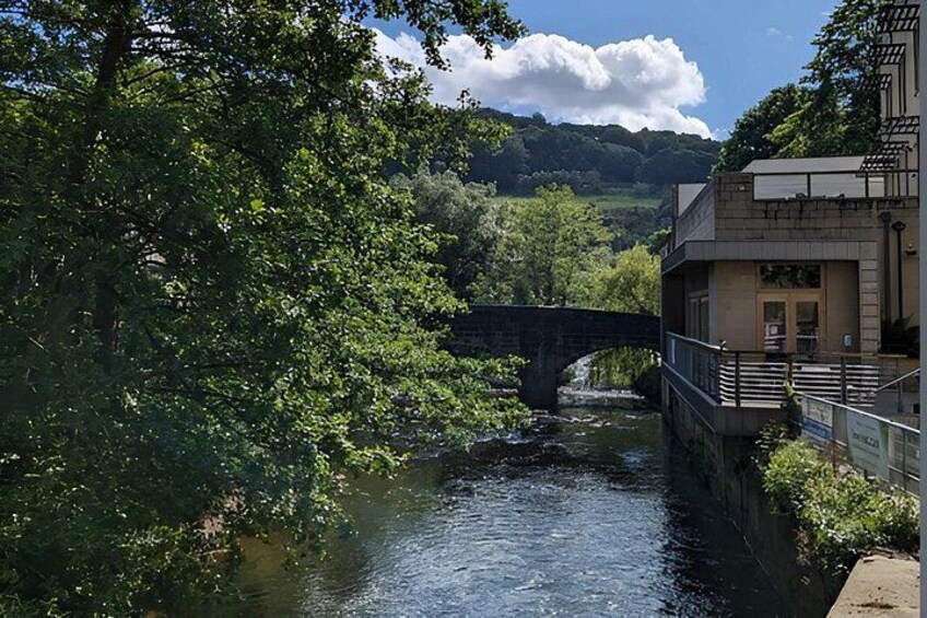 A river with a bridge, lush greenery, and a building with a balcony. 3