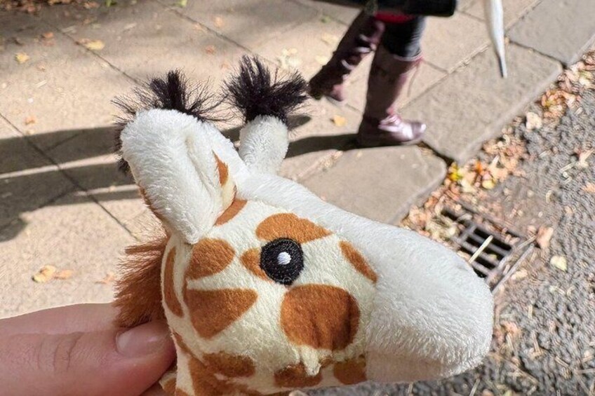 A giraffe plush toy with a human hand holding it. 2