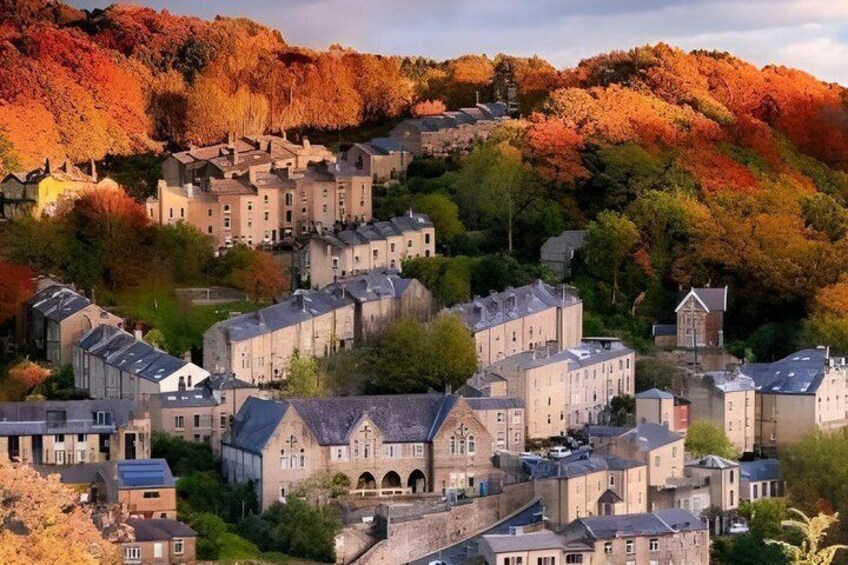 A town with historic buildings nestled in a valley, surrounded by autumn-colored trees. 3