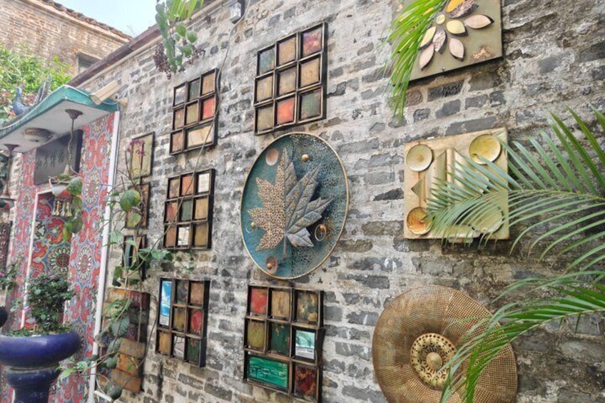 A stone building with decorative elements including a large leaf motif, a woven basket, and various framed pictures. 3