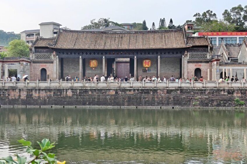 A traditional Chinese building with a tiled roof, a stone wall, and a reflection in the water. 5