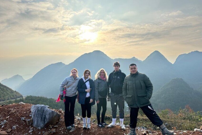 A group of people standing on a mountain ridge with a mountainous landscape in the background. 3
