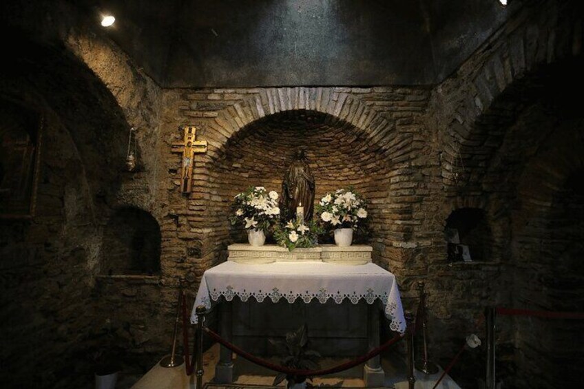 A stone chapel with a cross, altar, and flowers. 4