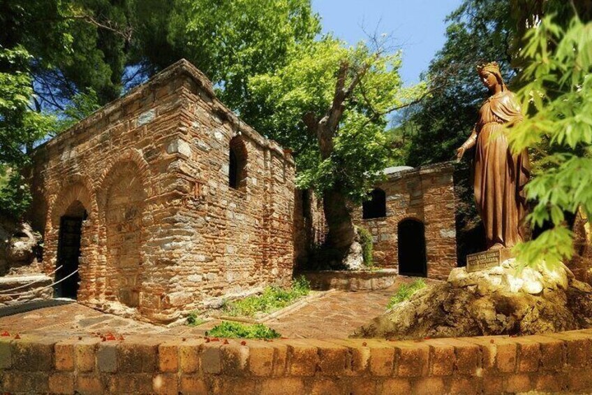 An ancient stone building with arched doorways, a statue, and lush greenery. 5