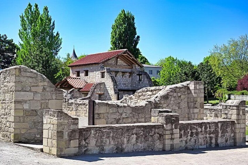 Ancient stone ruins with a modern building in the background. 5