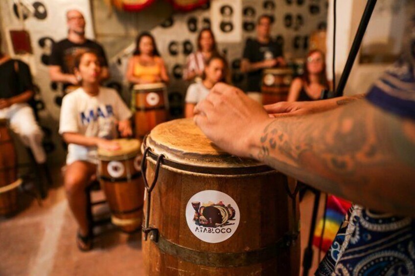 A person playing a drum with a logo that reads 'ATABOCO.' 1