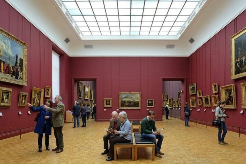 An art gallery with red walls and a high ceiling. 5