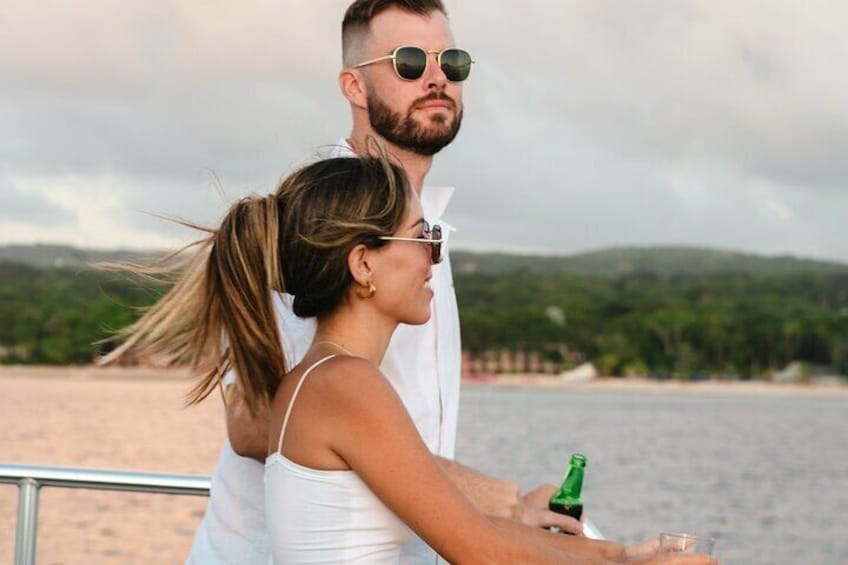 A couple on a boat with a beach and trees in the background. 4