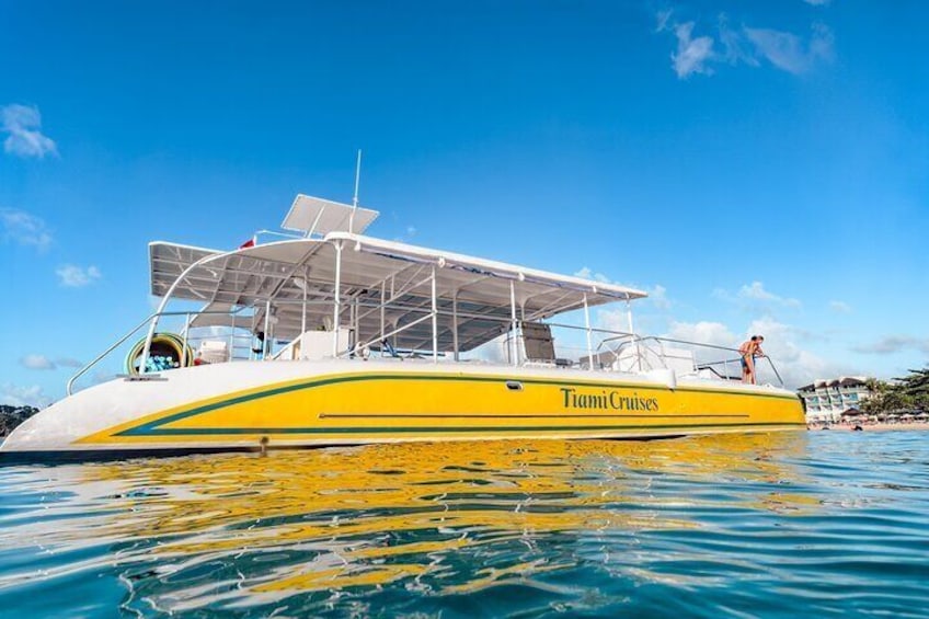 A yellow boat with the text 'Miami Cruises' on its side, floating on clear blue water. 1