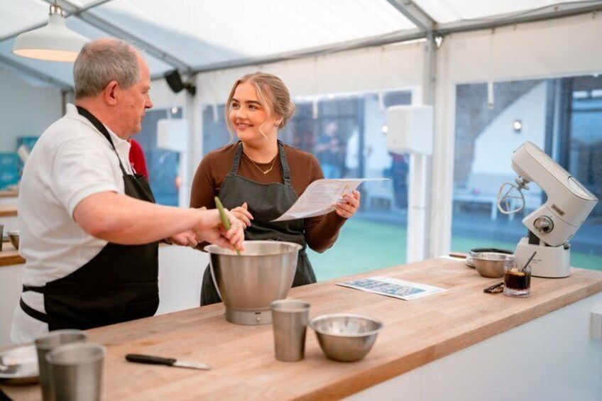 A person cooking with a large mixing bowl and a stand mixer on a wooden counter. 2