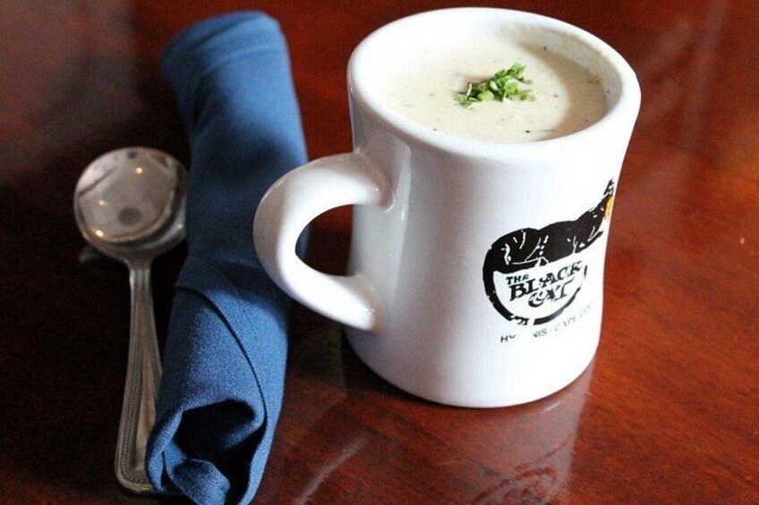 A white mug with a logo, a spoon, and a blue napkin on a wooden table. 3