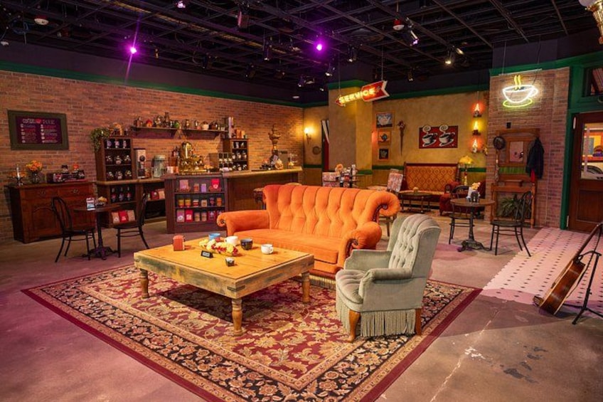 A vintage-themed room with a tufted orange sofa, a wooden coffee table, and a patterned rug. 3