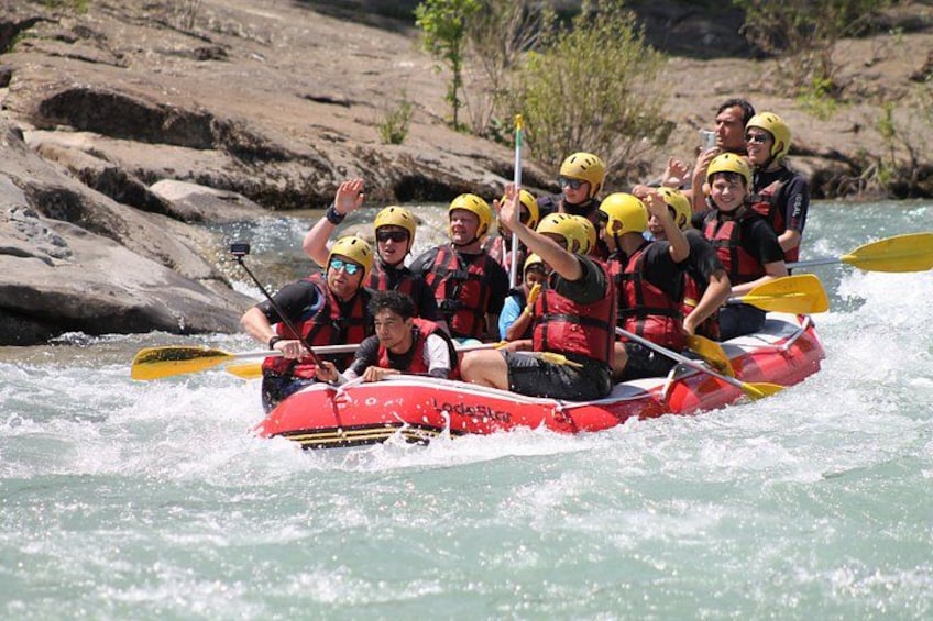 A group of people in a red raft navigating a river with rapids. 1