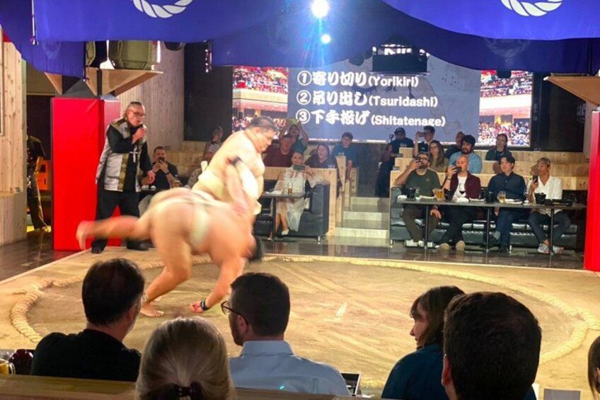 A sumo wrestling match with a crowd watching. 2