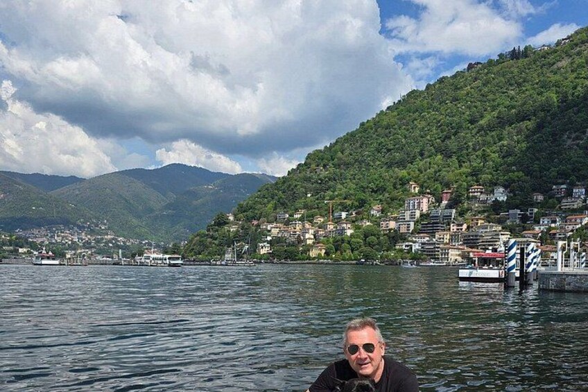 A lake with boats, a dock, and a hillside with buildings. 3