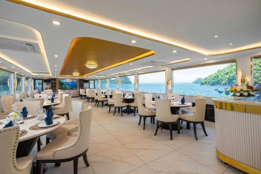 A spacious restaurant with tables and chairs, large windows, and a view of the sea. 4