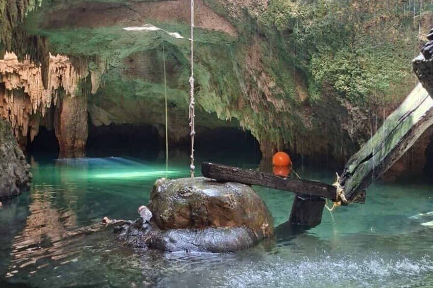 A cave with stalactites, a hanging rope, and a person fishing. 2