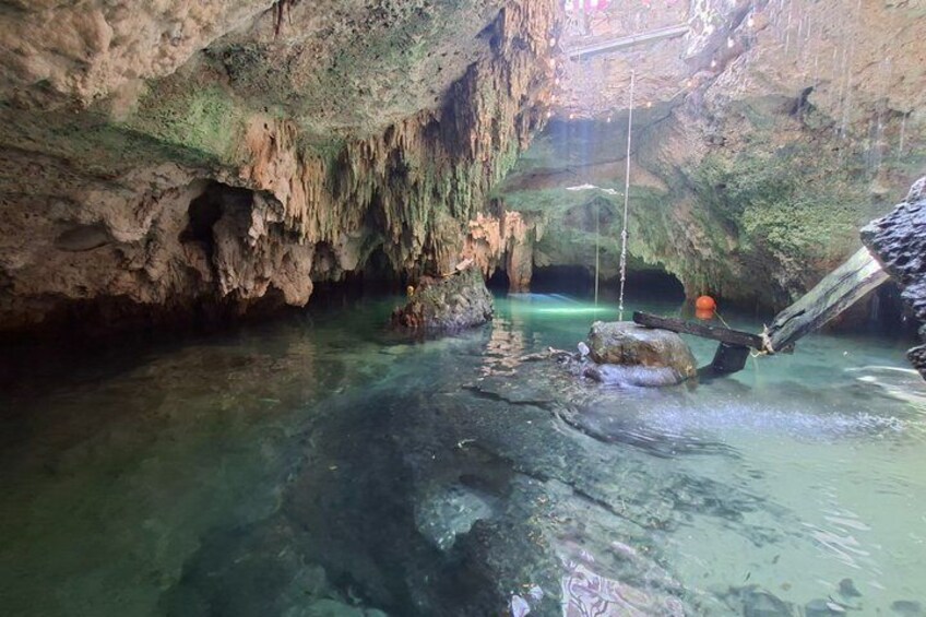 A cave with clear water, stalactites, and a rope bridge. 1