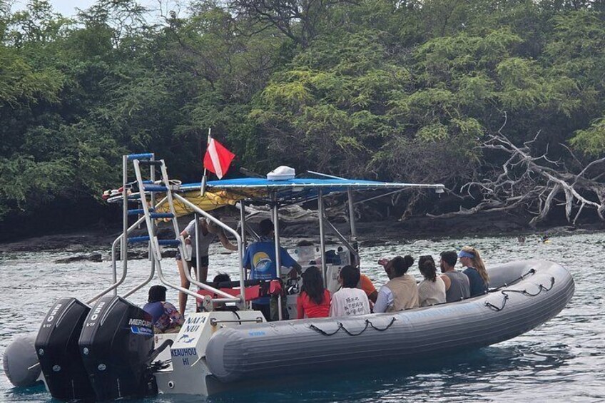 A group of people on a small inflatable boat with a flag, surrounded by water and trees. 5