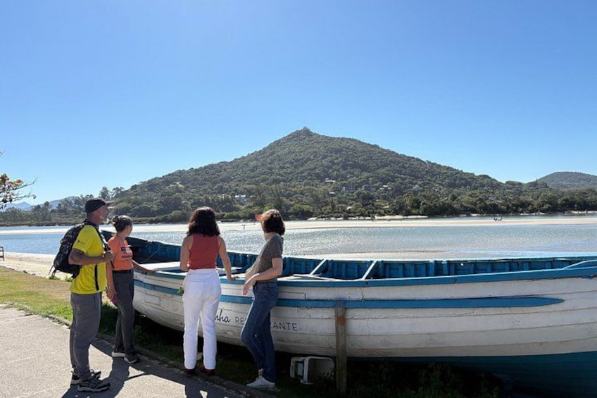 A group of people standing by a boat on a lake with a mountain in the background. 3