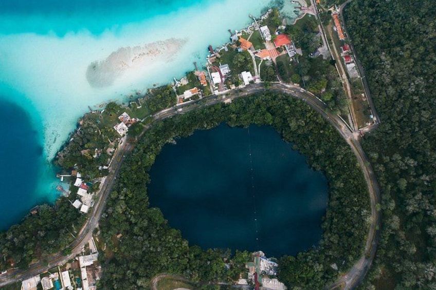 An aerial view of a coastal area with a large body of water, a road encircling a central island, and buildings along the coastline. 1