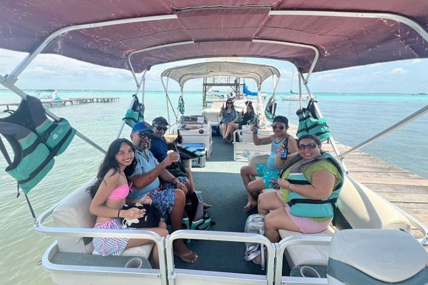 A group of people on a boat with a clear view of the turquoise sea and a pier in the background. 2
