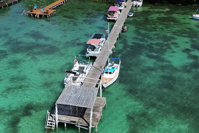 A pier with boats docked, clear turquoise water, and a wooden walkway. 3