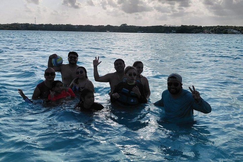 A group of people in a body of water, some holding a volleyball. 5
