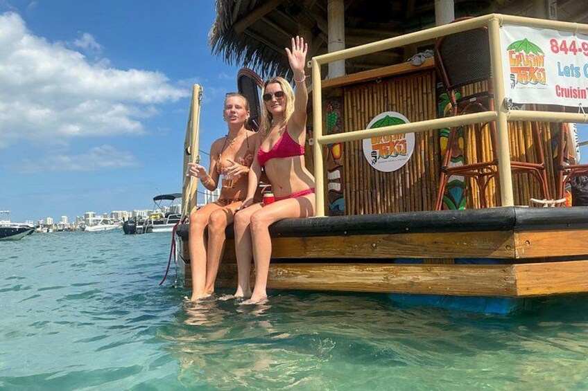 Two people on a boat in a tropical setting with clear water and a dock in the background. 2
