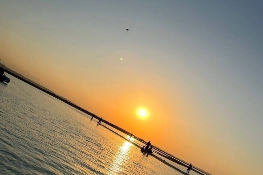 A sunset over a body of water with a bridge and people walking. 2