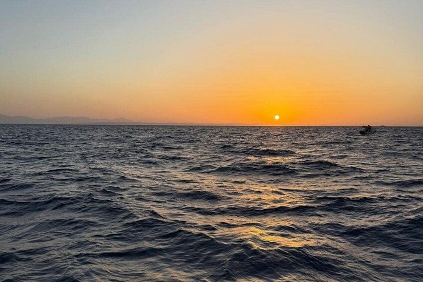 A sunset over the ocean with waves and a distant boat. 3