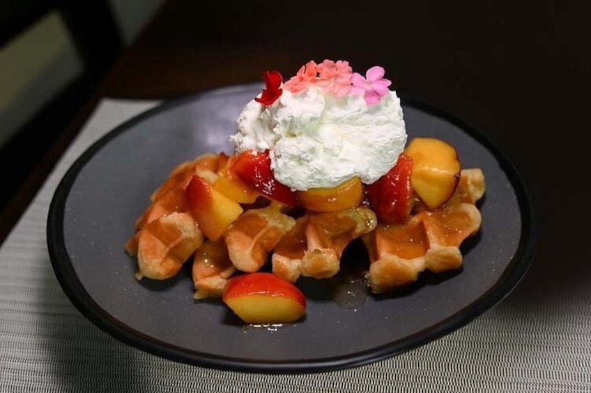 A plate of waffles topped with whipped cream and fruit. 3