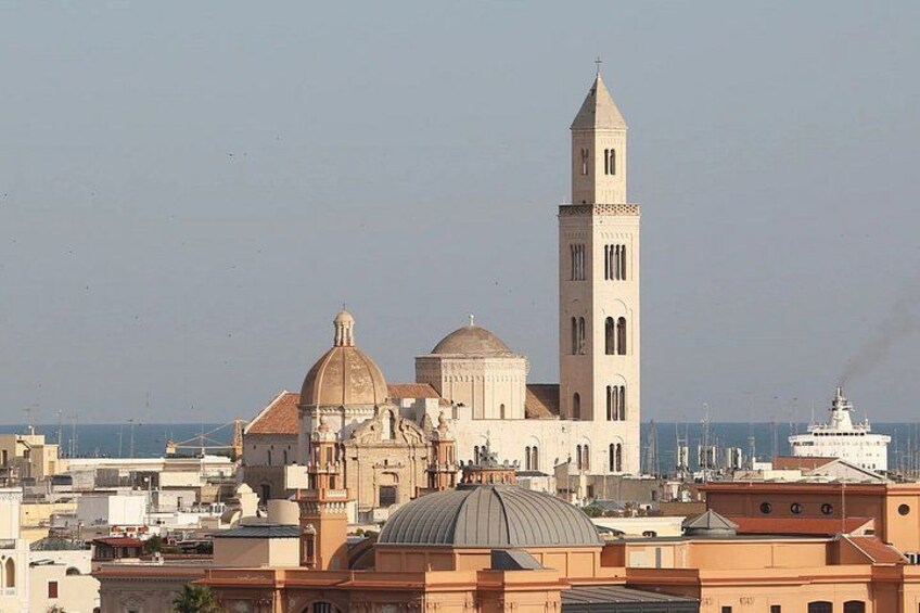 A coastal cityscape with a prominent church featuring a tall bell tower and domed structures. 3