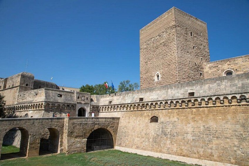 A historic stone wall with arched gateways and a tall square tower. 4