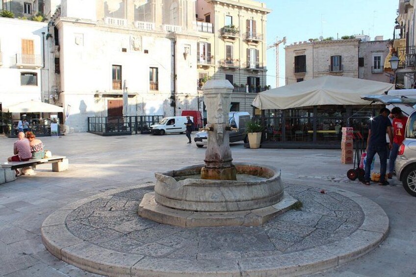 A public square with a central fountain, benches, and surrounding buildings. 5