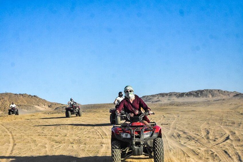 A desert landscape with four off-road vehicles and riders. 4