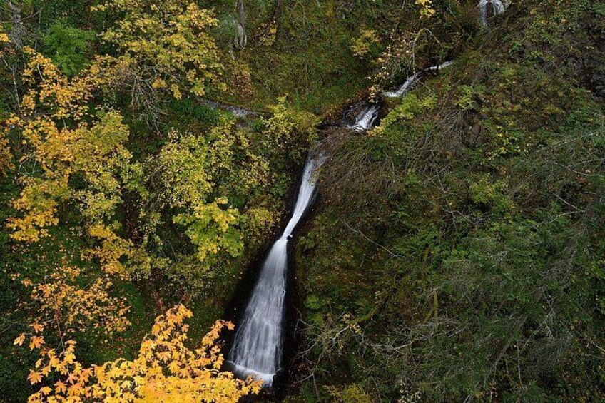 A waterfall cascading down a rocky slope surrounded by autumn foliage. 4