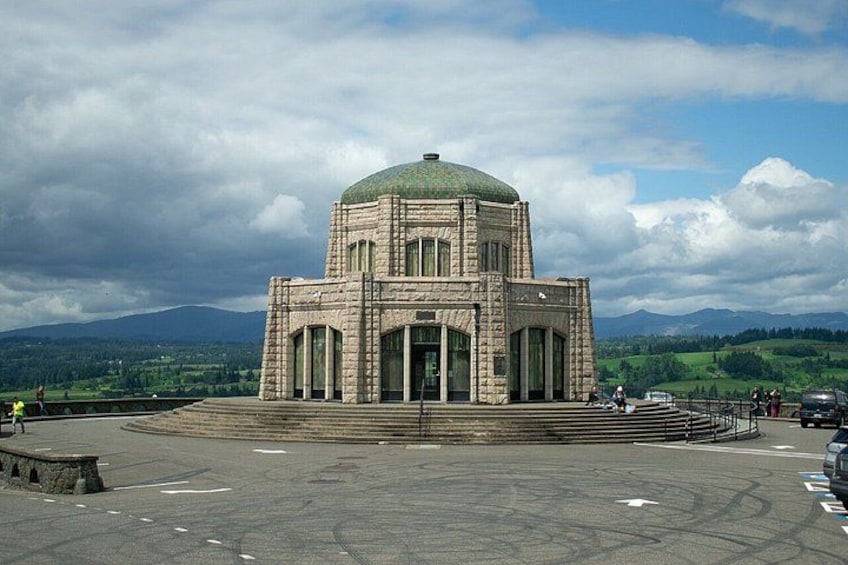 A large stone building with a dome, surrounded by a paved area and a mountainous landscape. 2