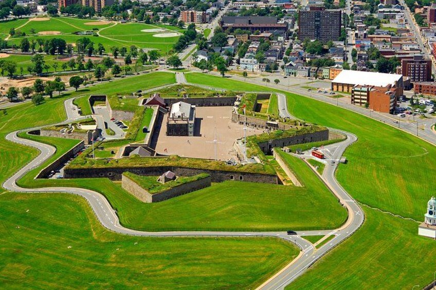 An aerial view of a park with a central fort-like structure, surrounded by green fields and roads. 2
