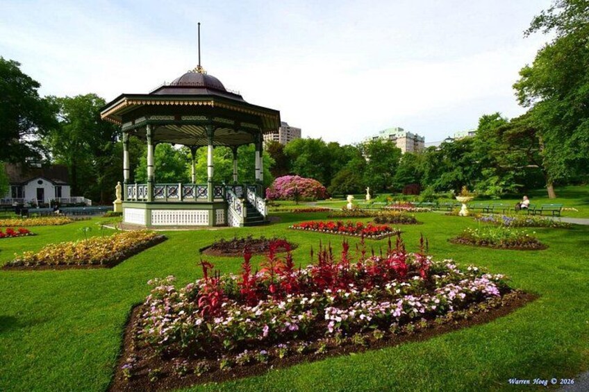 A gazebo in a park with flower beds and trees. 3