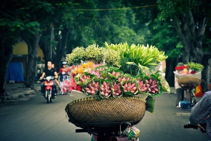 A street scene with a cart loaded with flowers and plants. 1
