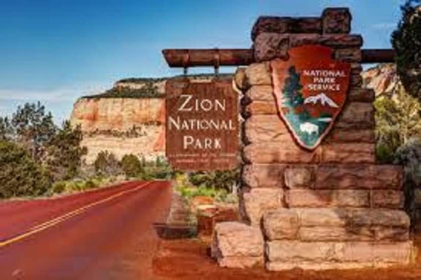 Zion National Park entrance with a sign and a stone wall. 3