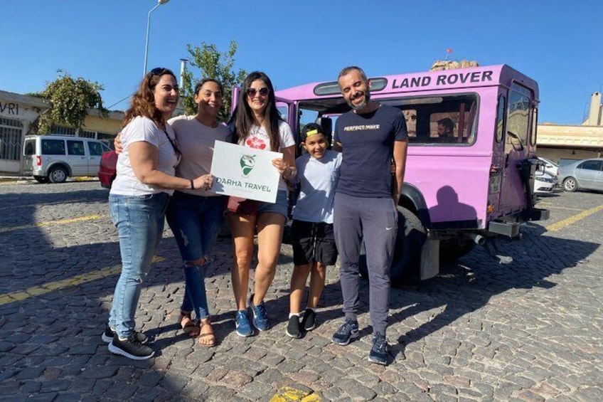 A group of people standing in front of a purple Land Rover vehicle with a sign that reads 'DARHA TRAVEL'. 1