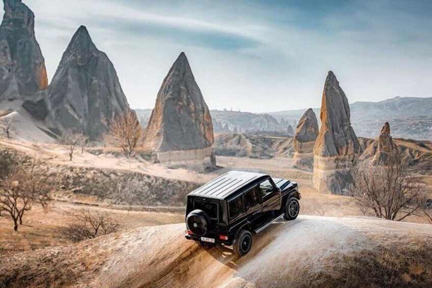 A vehicle on a dirt road with rock formations in the background. 5