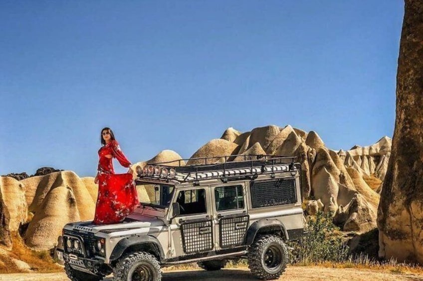 A desert landscape with a vehicle and a person in a red dress. 3