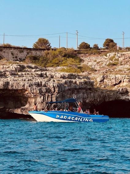 A blue boat named 'Parasailing' with people on board, near rocky cliffs and power lines. 3