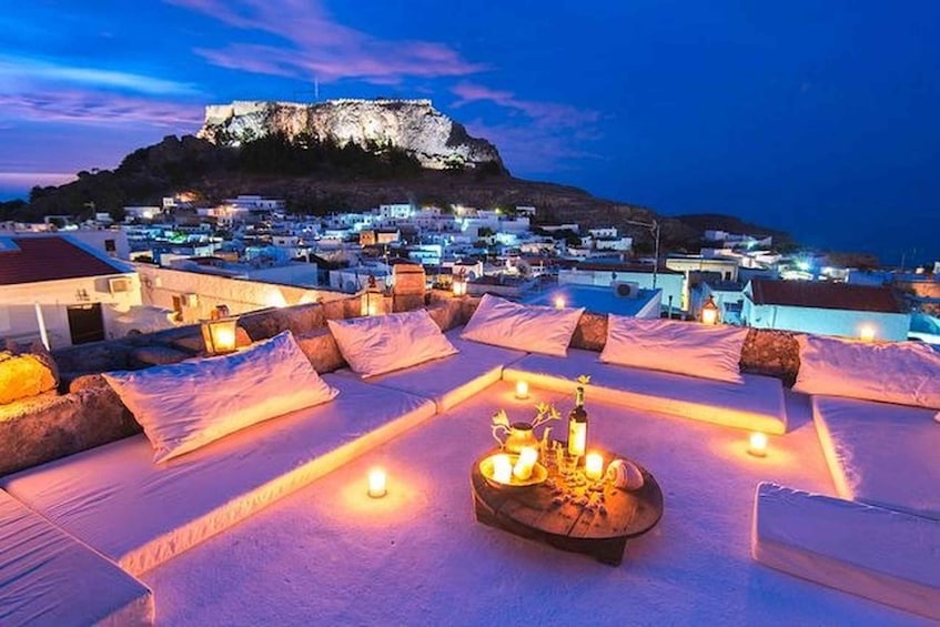 A rooftop lounge with a view of a town and a hill. 5
