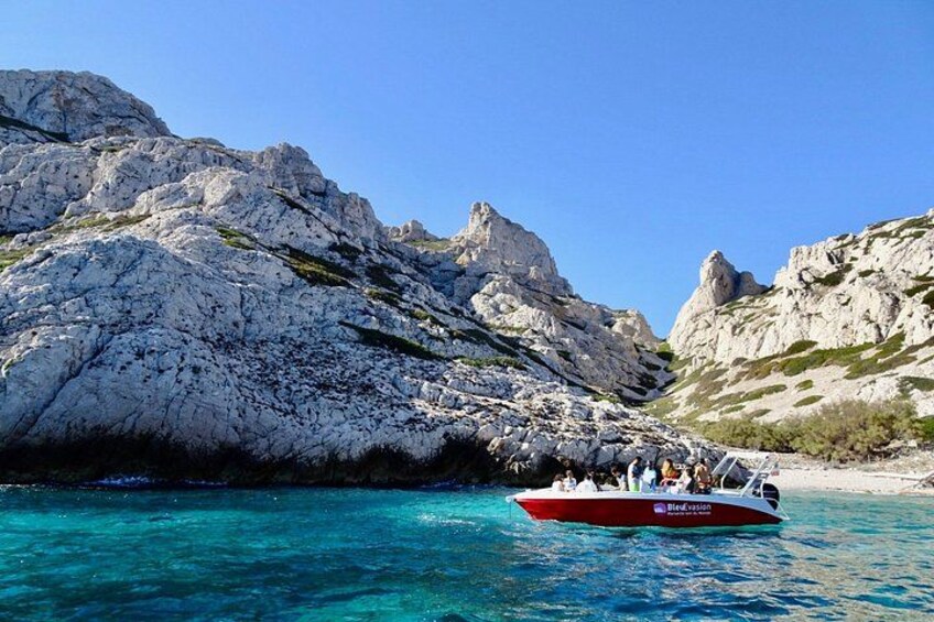 A boat on turquoise water with rocky cliffs in the background. 5
