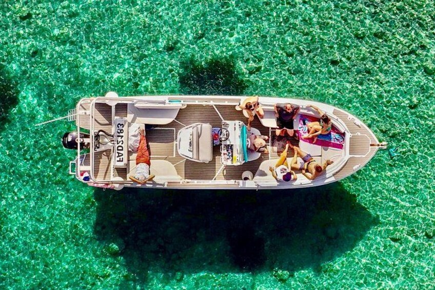 A boat with people on a clear, greenish water surface. 1