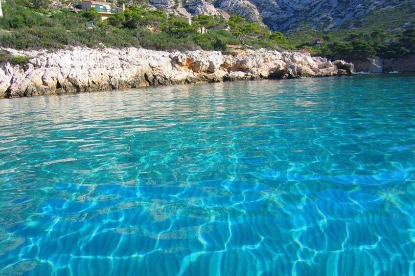 Clear turquoise water, rocky shoreline, and green vegetation. 2
